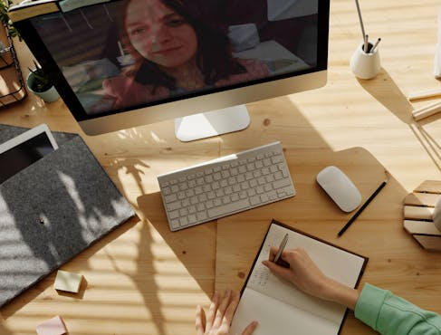 A person attending an online meeting on a computer, engaging in remote learning or training.